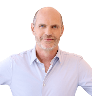 Portrait of a smiling middle-aged man with light stubble, wearing a pale blue button-down shirt against a neutral backdrop.